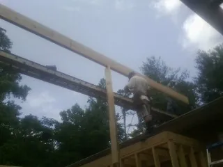 Carpenter setting a ridge beam over a new addition frame — Ice Dam Removal by Roofing Brothers in Millican