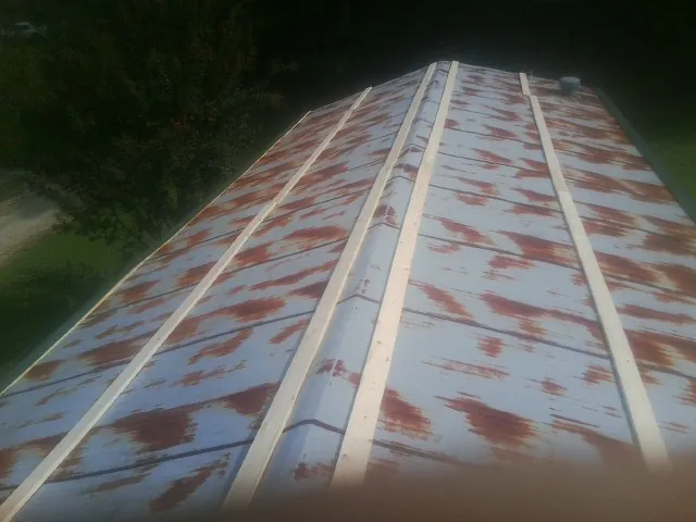 Rusted metal roof panels with new wood purlins before replacement — Storm Damage Roof Repair in Millican by Roofing Brothers