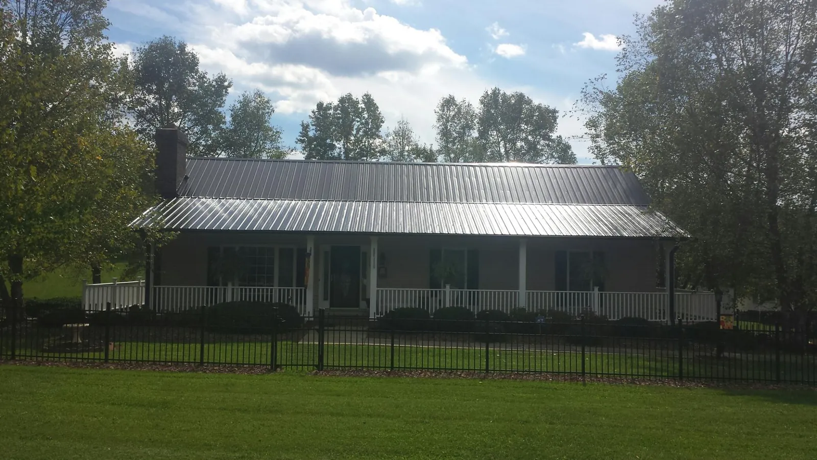 Gray metal roof on a brick ranch with a full width front porch — Gutter Guard Installation work by our crew in Millican