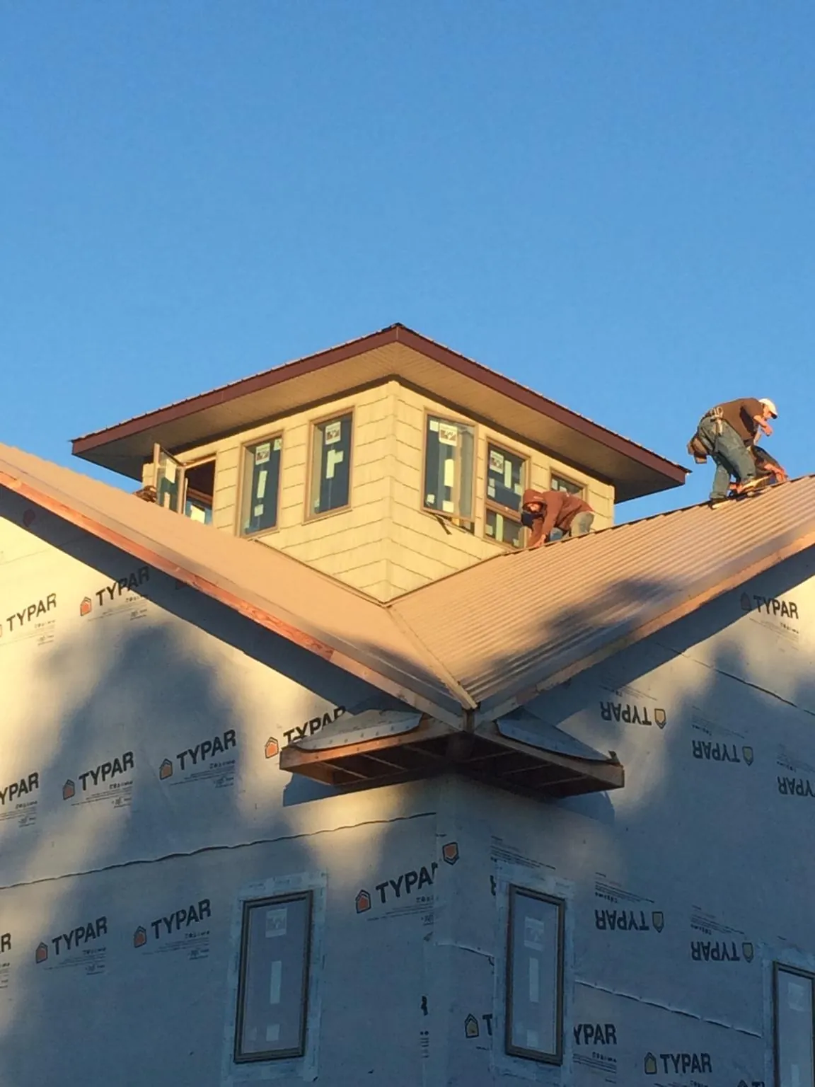 Roofers working around a rooftop cupola on a new metal roof at sunset — Roof Waterproofing in Millican by Roofing Brothers